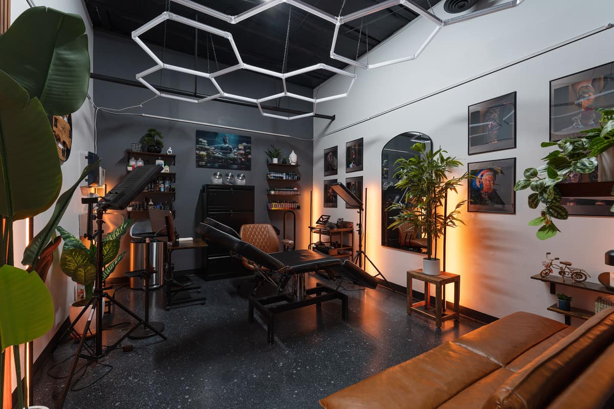 A finished private suite at Certified Tattoo Suites: hex light panels, black ceiling, tattoo chair and couch